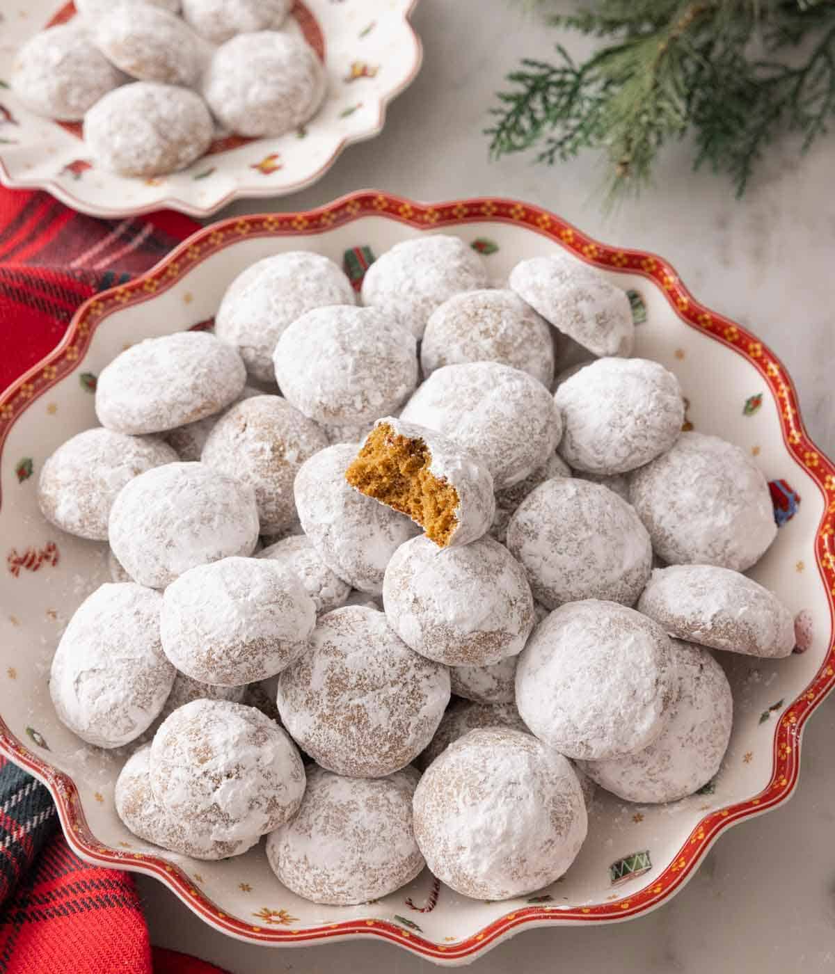 A platter with a pile of Pfeffernusse cookies with one bitten on top.