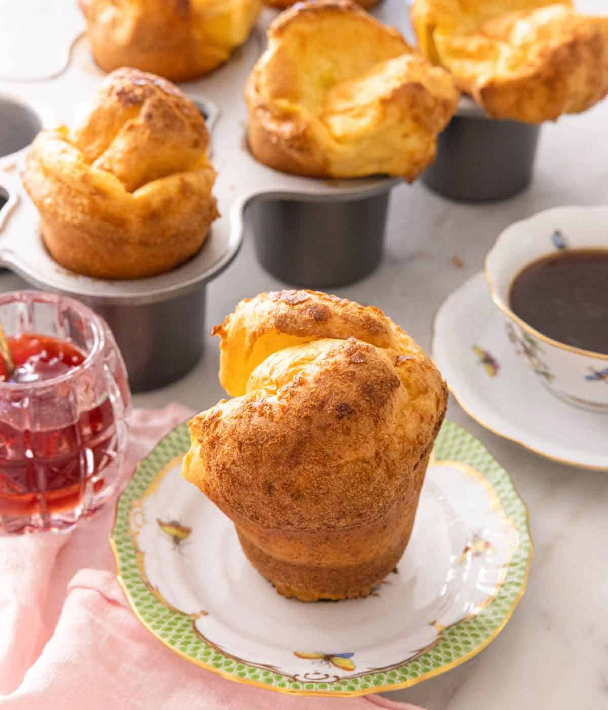 A popover on a plate in front of a baking pan with more.
