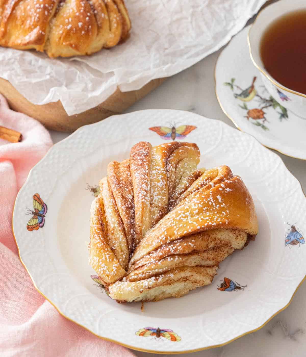 A serving of star bread on a plate by a cup of tea.