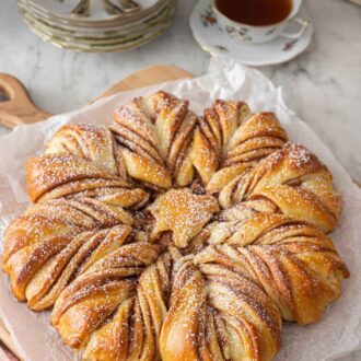 Pinterest graphic of a star bread on a piece of parchment on a cutting board.