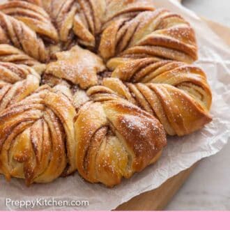 Pinterest graphic of a star bread with a dusting of powdered sugar on top on a serving board.