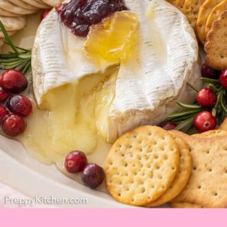 Pinterest graphic of a baked brie with honey and jam on top, cut opened.