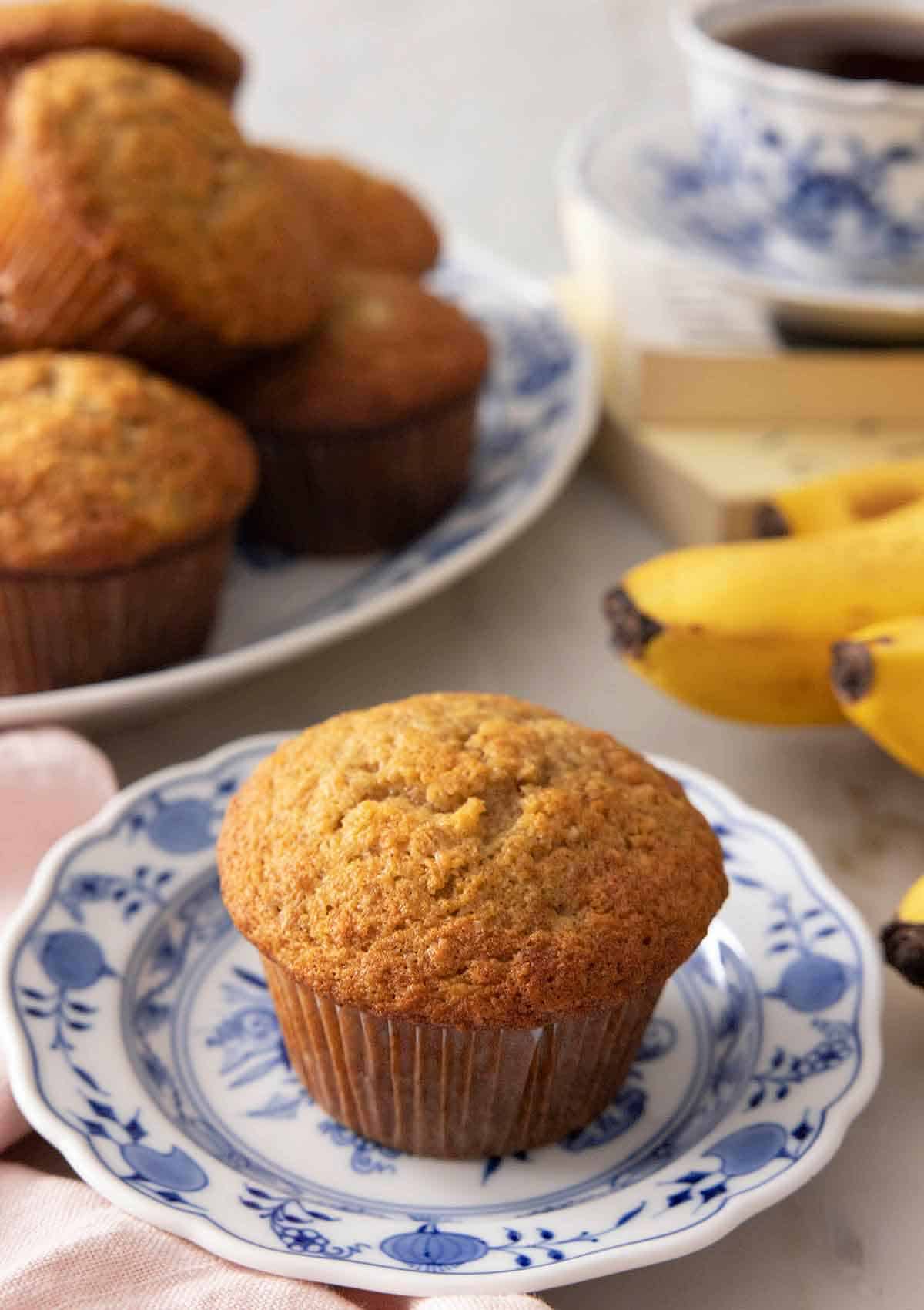 A plate with a banana muffin with a platter in the back.