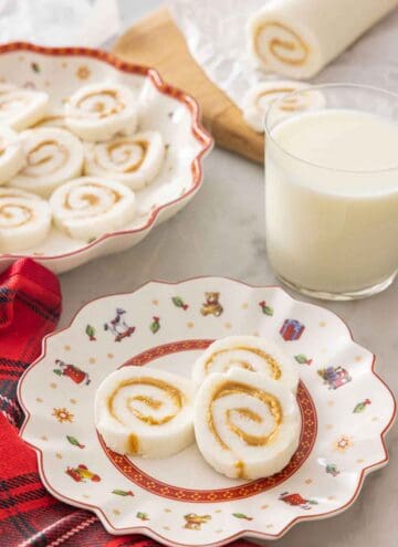 A plate with three pieces of potato candy by a glass of milk.