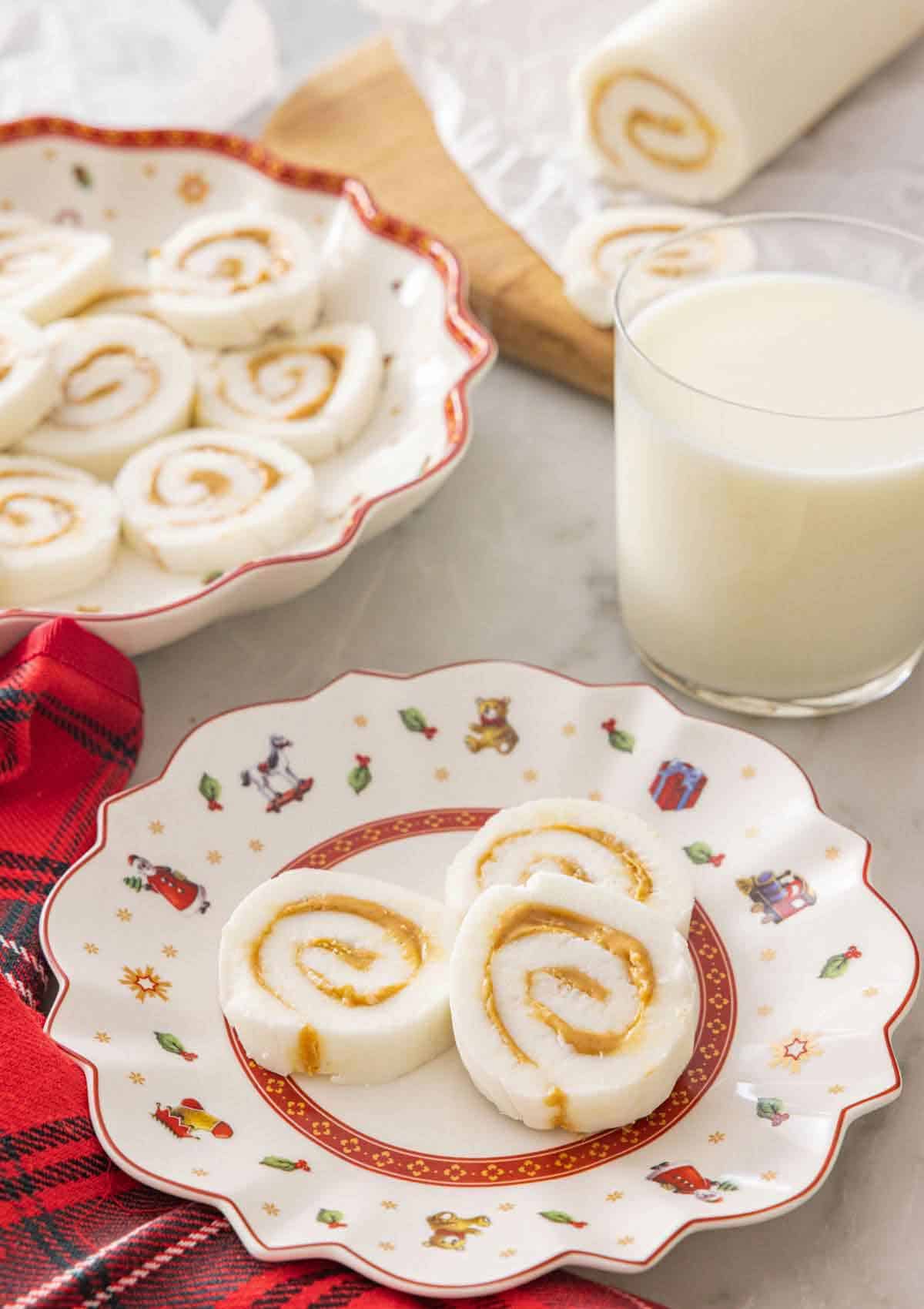 A plate with three pieces of potato candy by a glass of milk.