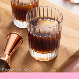 Pinterest graphic of two glasses of Black Russians on a wooden serving board.
