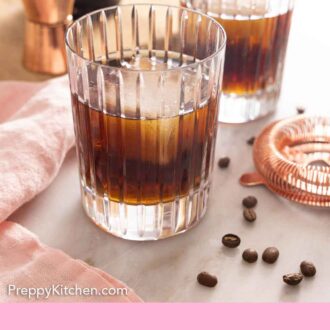 Pinterest graphic of a glass of Black Russian with coffee beans and equipment scattered around.