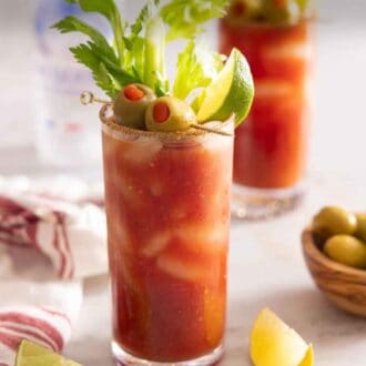 Pinterest graphic of a glass of Bloody Mary with olives, lime, and celery garnish.