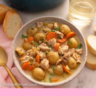 Pinterest graphic of a bowl of chicken stew by a glass of wine and some bread.