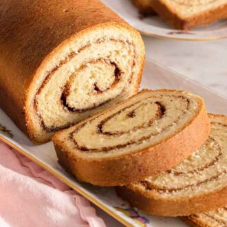A platter with cinnamon swirl bread, half sliced.