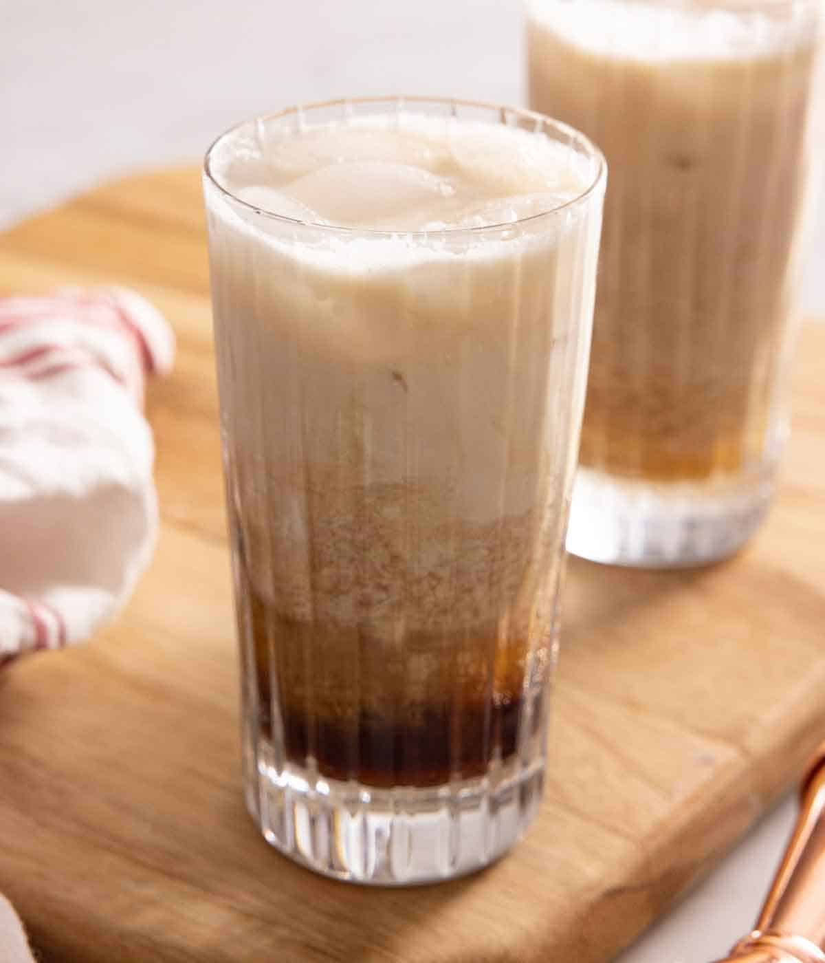 Two glasses of Colorado Bulldog cocktails on a wooden board.
