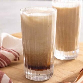 Two glasses of Colorado Bulldog cocktails on a board with a linen napkin beside it.