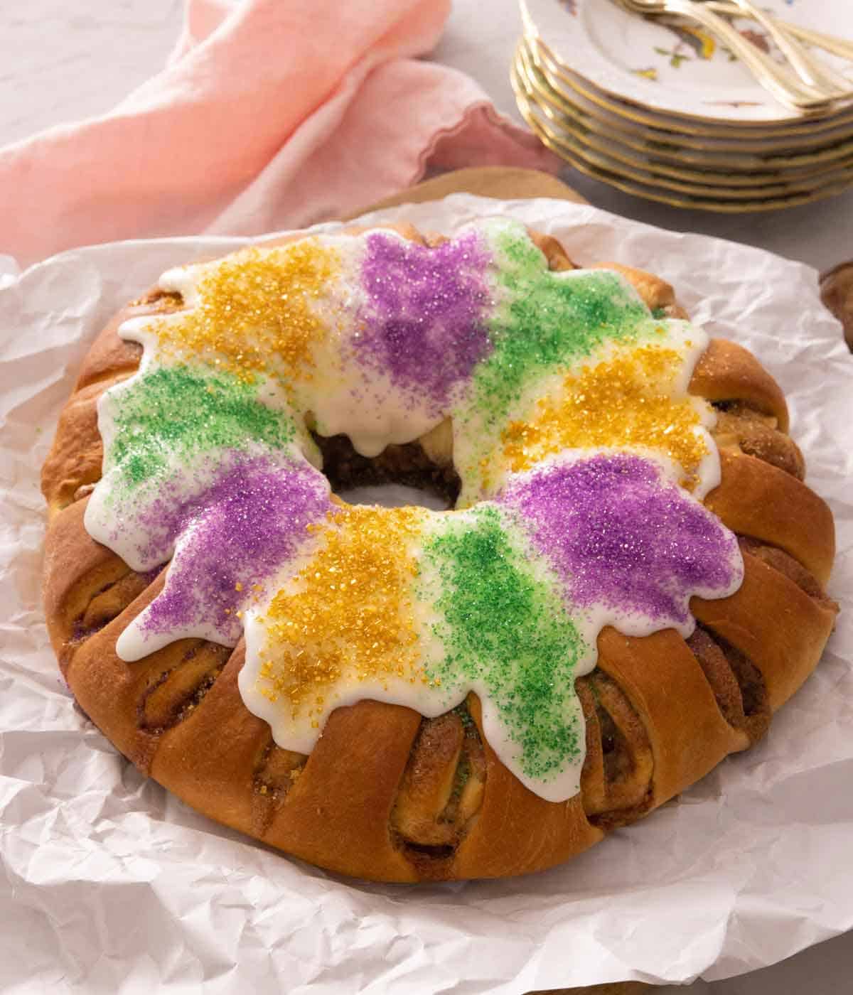 A king cake with icing on top with purple, yellow, and green sanding sugar.
