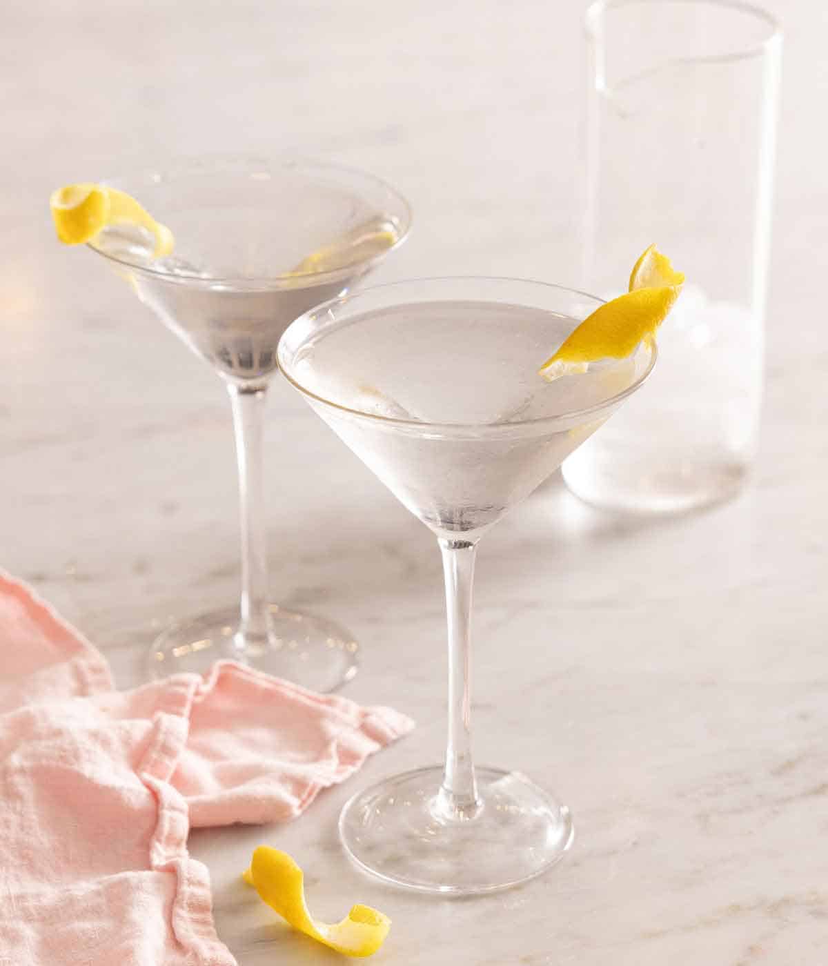 Two glasses of martinis with lemon garnishes.