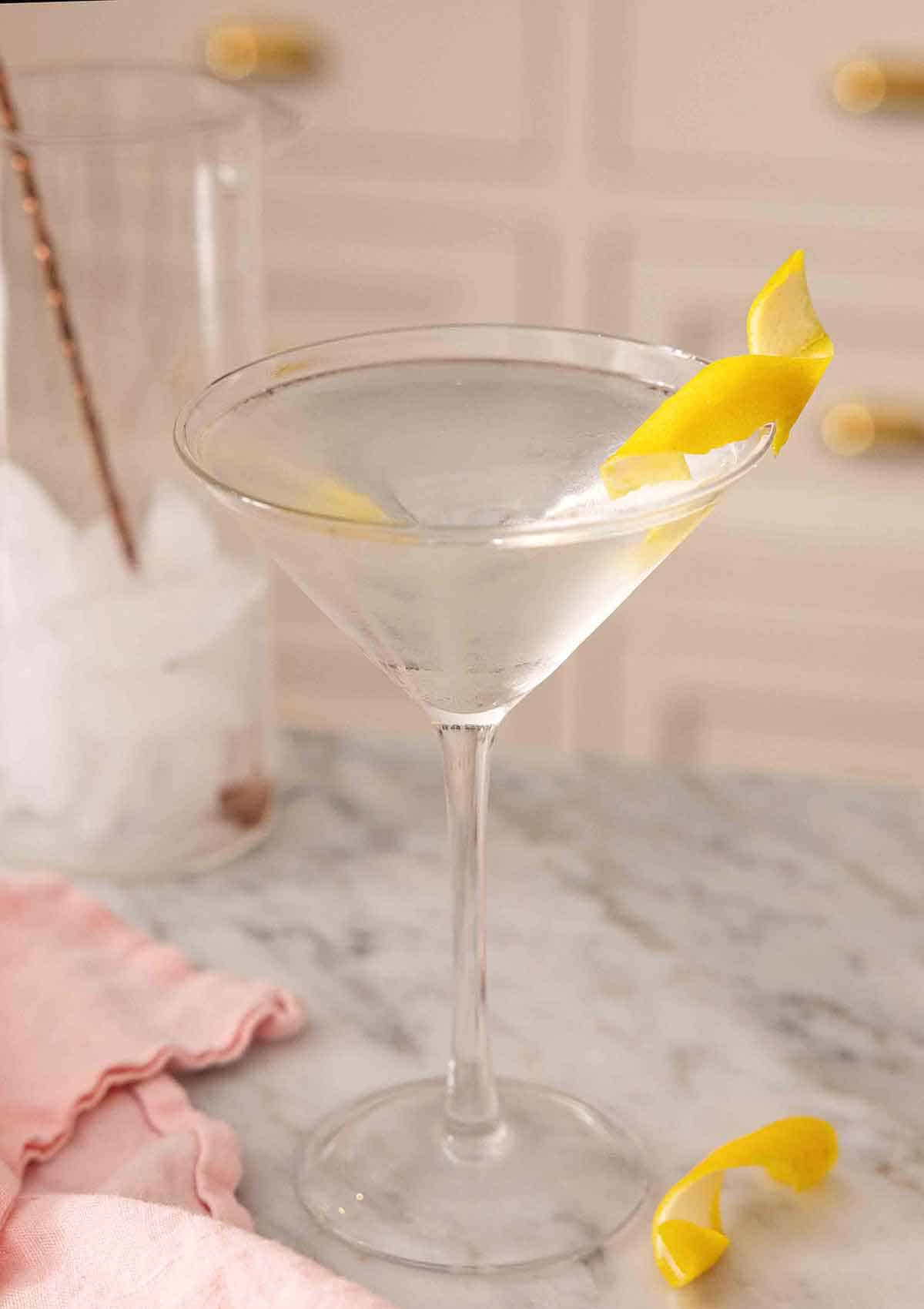 A glass of martini with a lemon twist garnish.