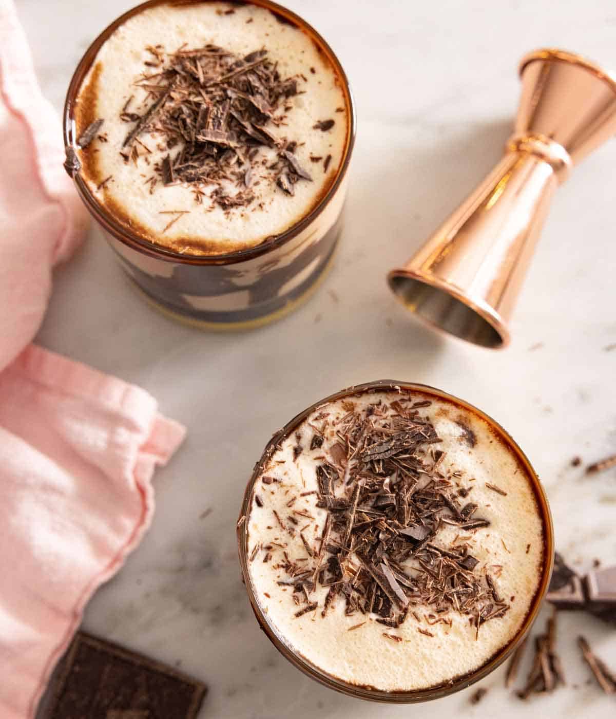 Overhead view of two glasses of mudslide with a jigger beside it.