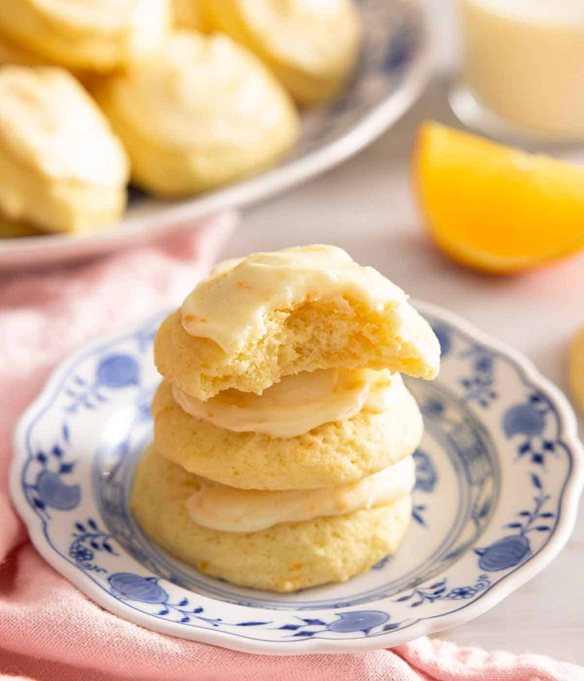 A plate with a stack of orange cookies with the top one with a bite taken out.