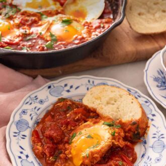 Pinterest graphic of a plate of shakshuka on a plate with a piece of bread.