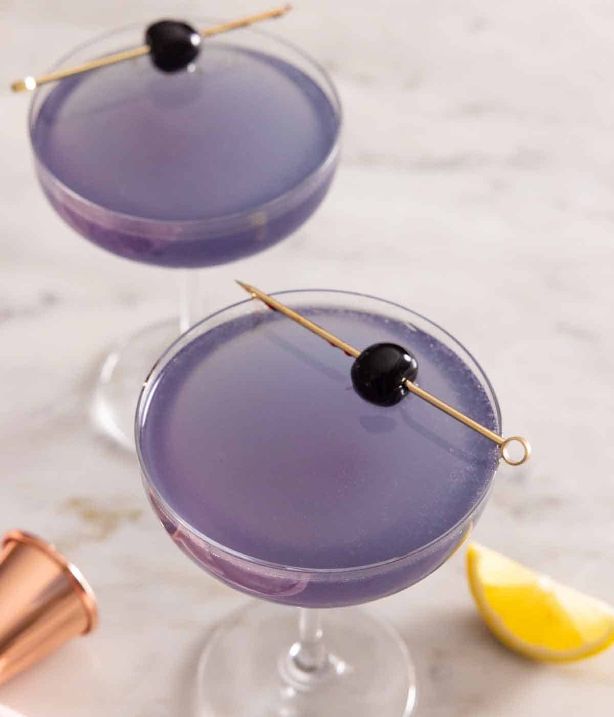 Overhead view of two glasses of Aviation cocktail with cocktail cherry garnish.