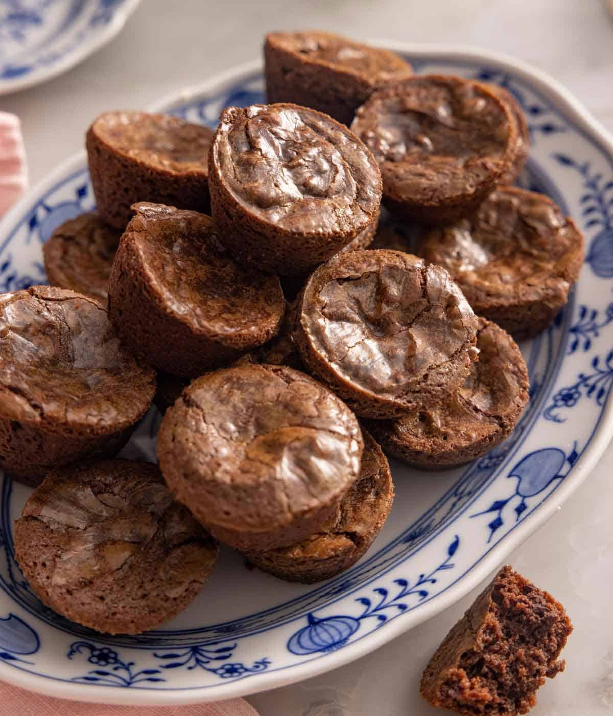 A platter with multiple brownie bites, with a few stacked on top of each other.