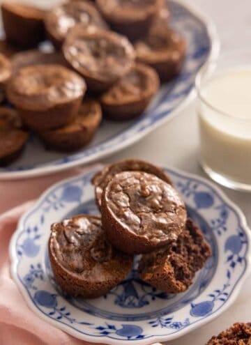 A plate with a stack of brownie bites, one with a bite taken out.