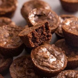 Multiple brownie bites stacked on top of each one with one on top with a bite taken out.
