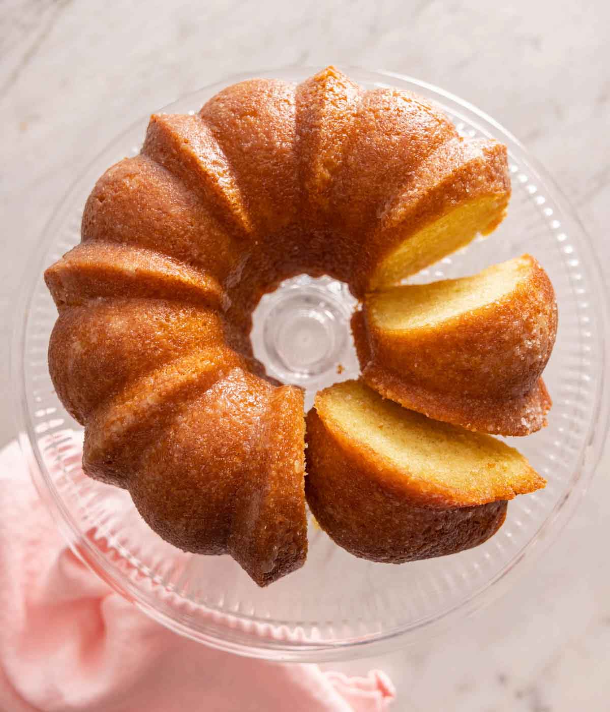 Overhead view of a butter cake on a cake stand with slices cut.
