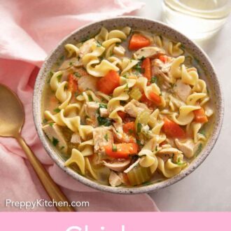 Pinterest graphic of a bowl of chicken noodle soup by a spoon and glass of wine.