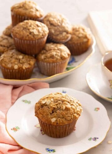 A plate with an oatmeal muffin with a platter in the back.