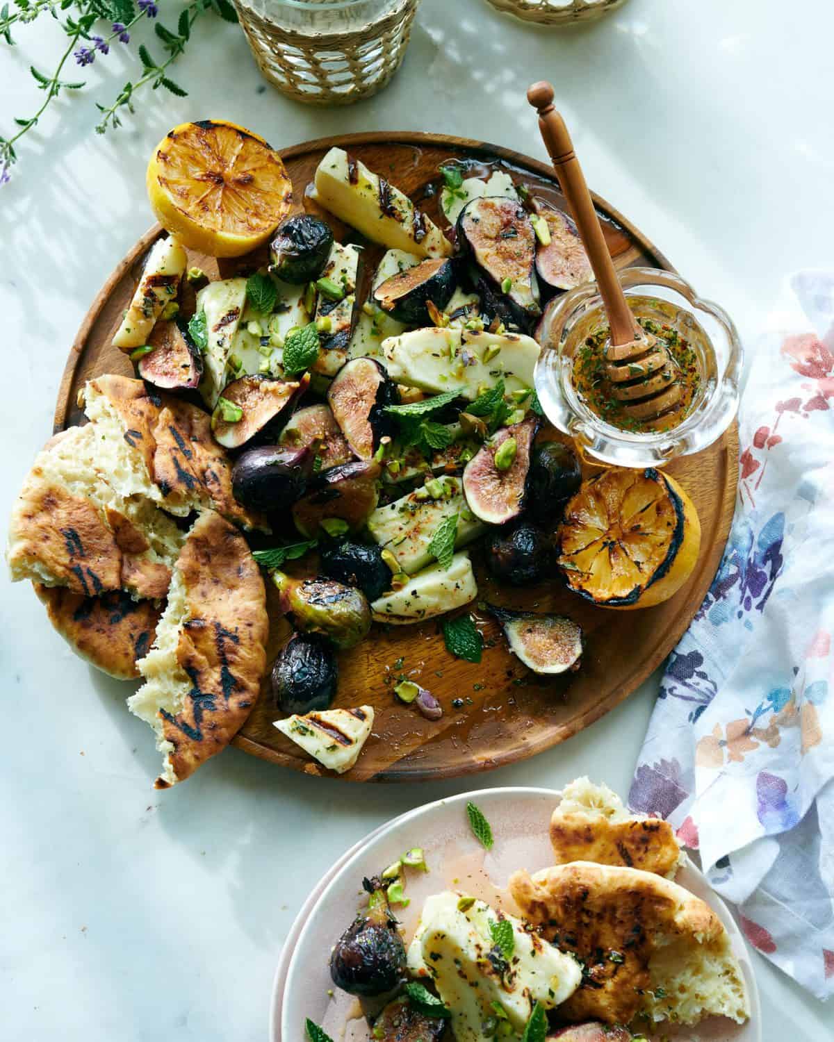 Grilled haloumi cheese with herbed honey and crusty pita bread on a wooden serving platter.