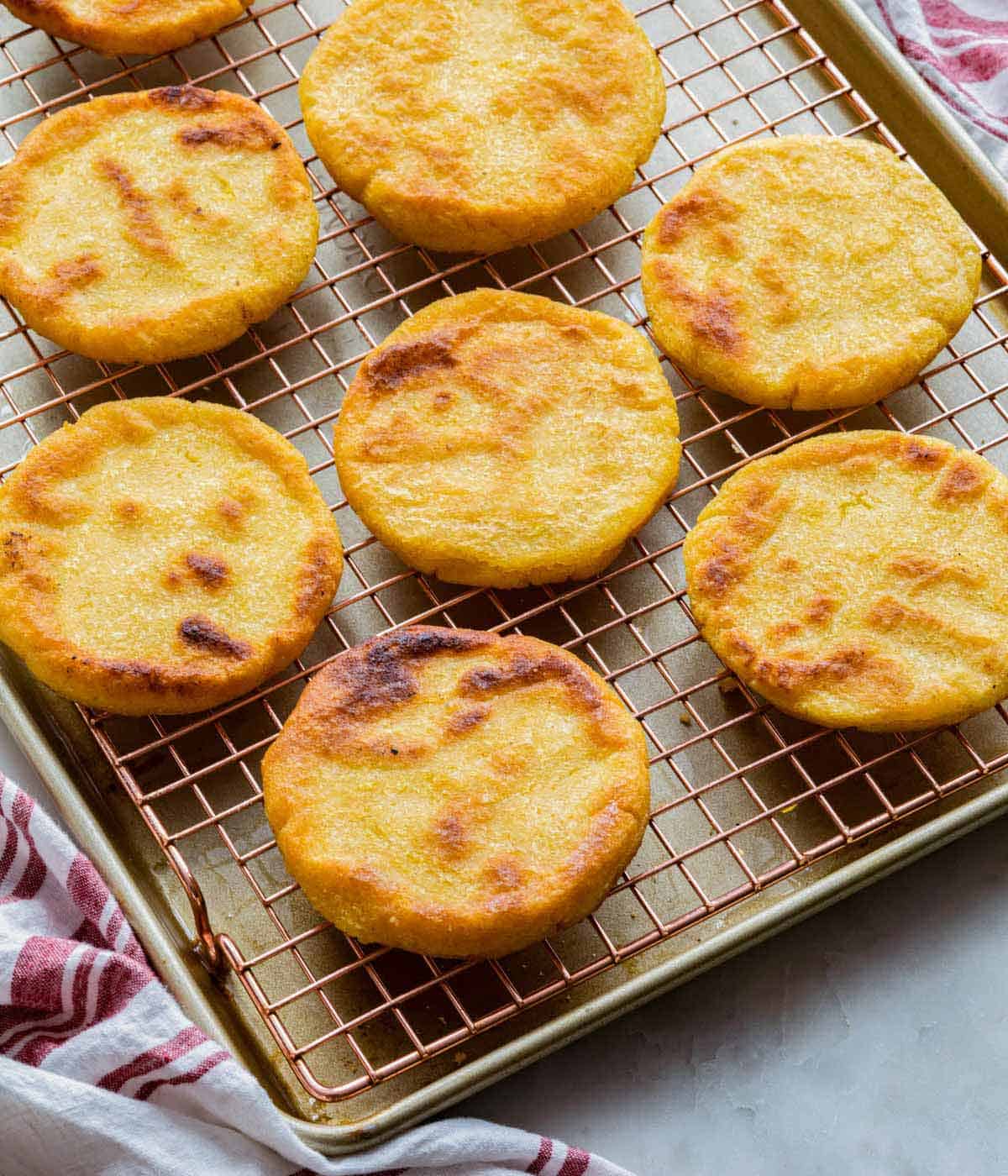 Multiple arepas on a wire cooling rack.