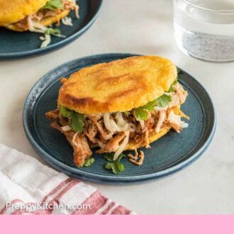 Pinterest graphic of a plate with an arepas, stuffed with meat.