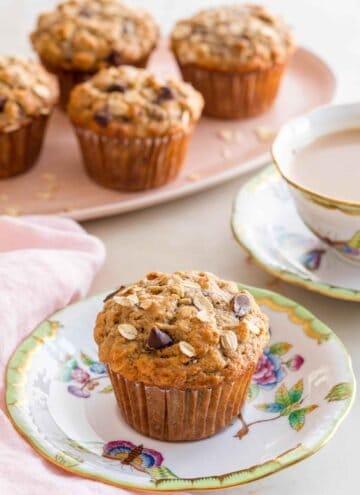 A plate with a banana oatmeal muffin with more muffins in the background.