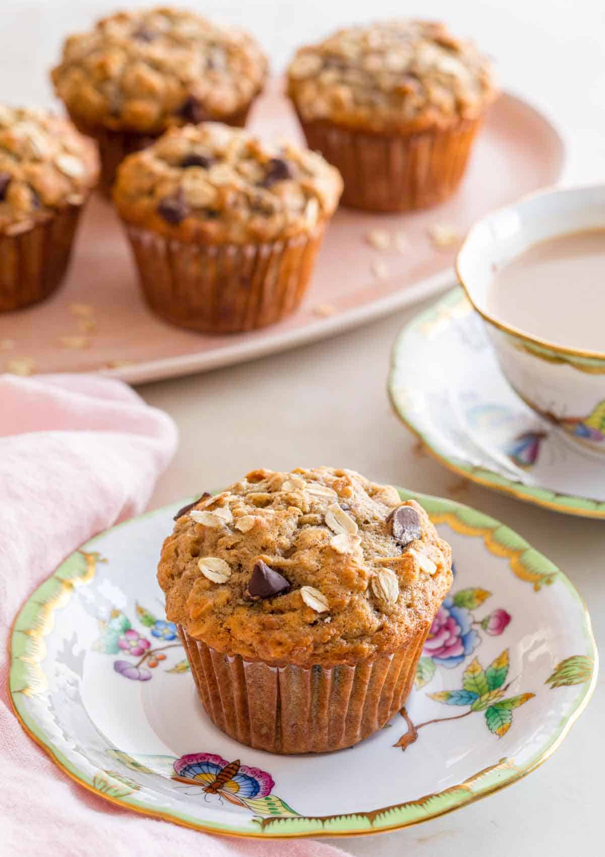 A plate with a banana oatmeal muffin with more muffins in the background.