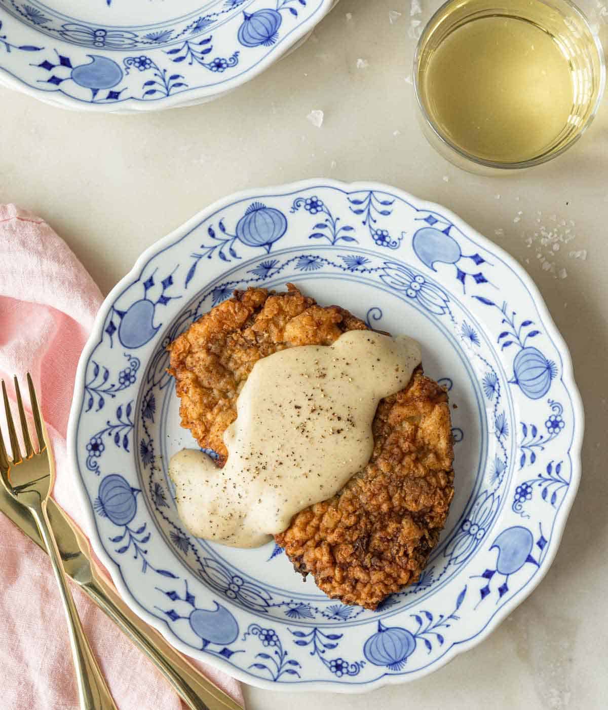 Overhead view of a plate of chicken fried steak with gravy on top.