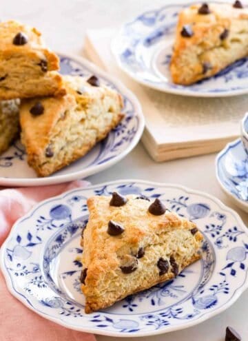 A chocolate chip scone on a plate with more in the background.