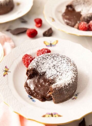 A plate with a chocolate lava cake with the molten center pouring out.