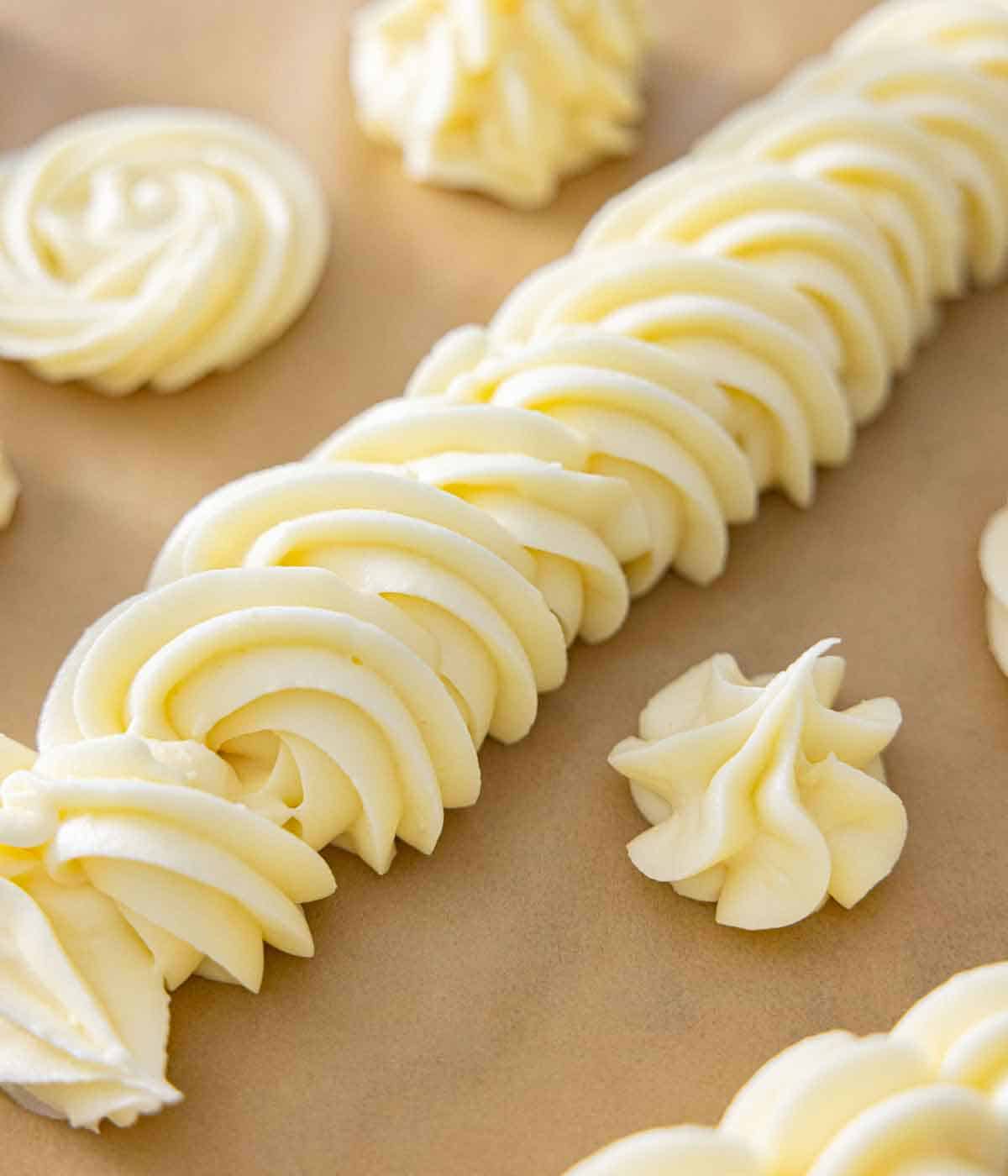 A piece of parchment paper with different styles of cream cheese frosting piped.