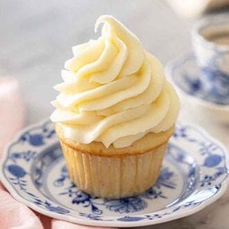 A cupcake with cream cheese frosting piped in a tall swirl.