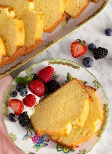 Overhead view of a plate with two slices of pound cake with berries and whipped cream.