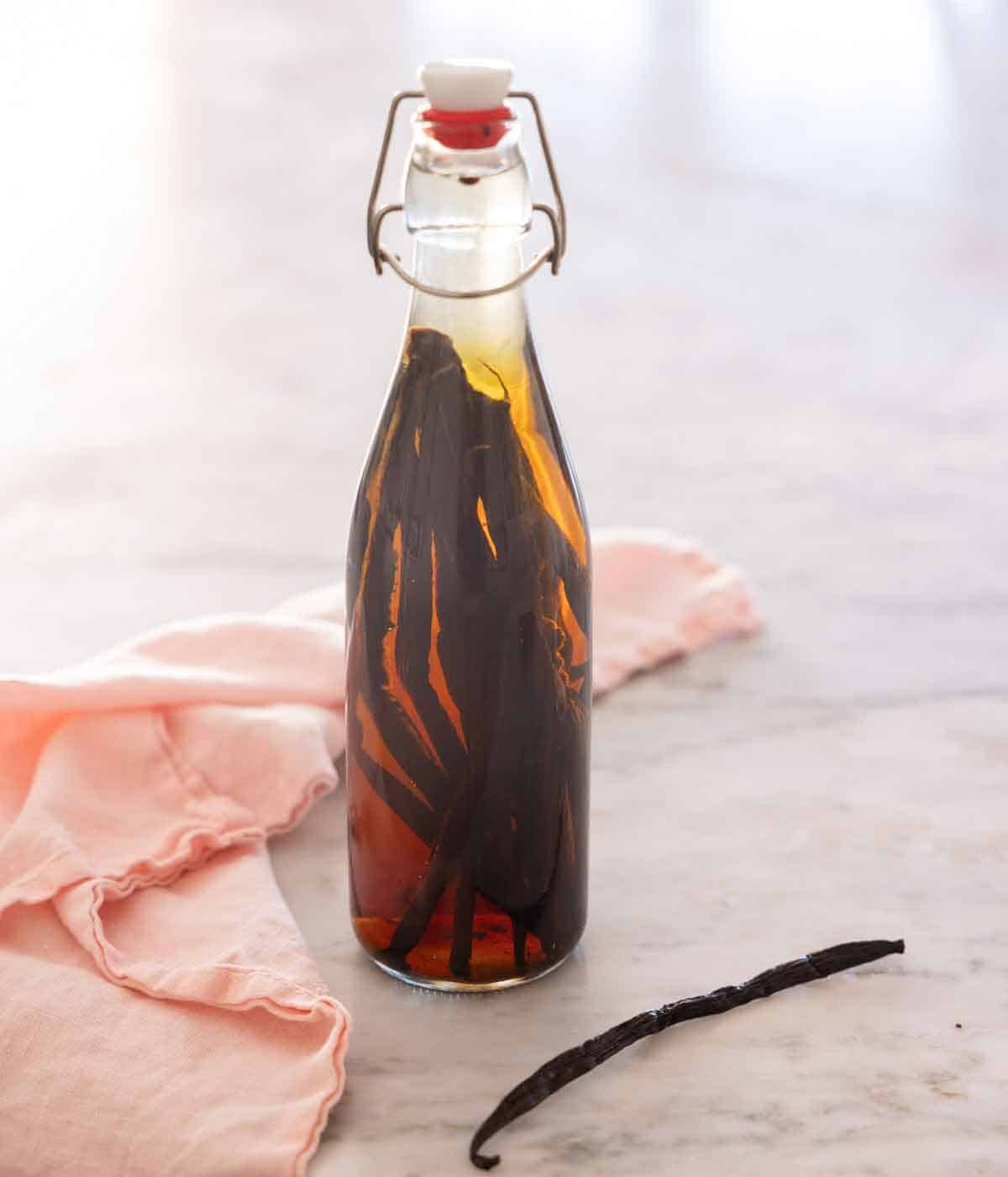 A jar of homemade vanilla extract with vanilla beans inside.