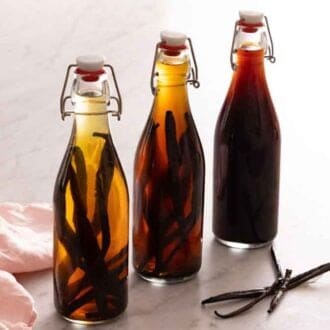 Three jars of homemade vanilla extract with varying darkness.