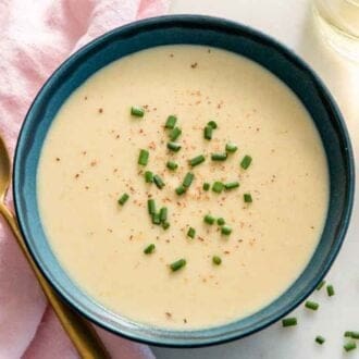 Overhead view of a bowl of vichyssoise by a spoon and glass of wine.