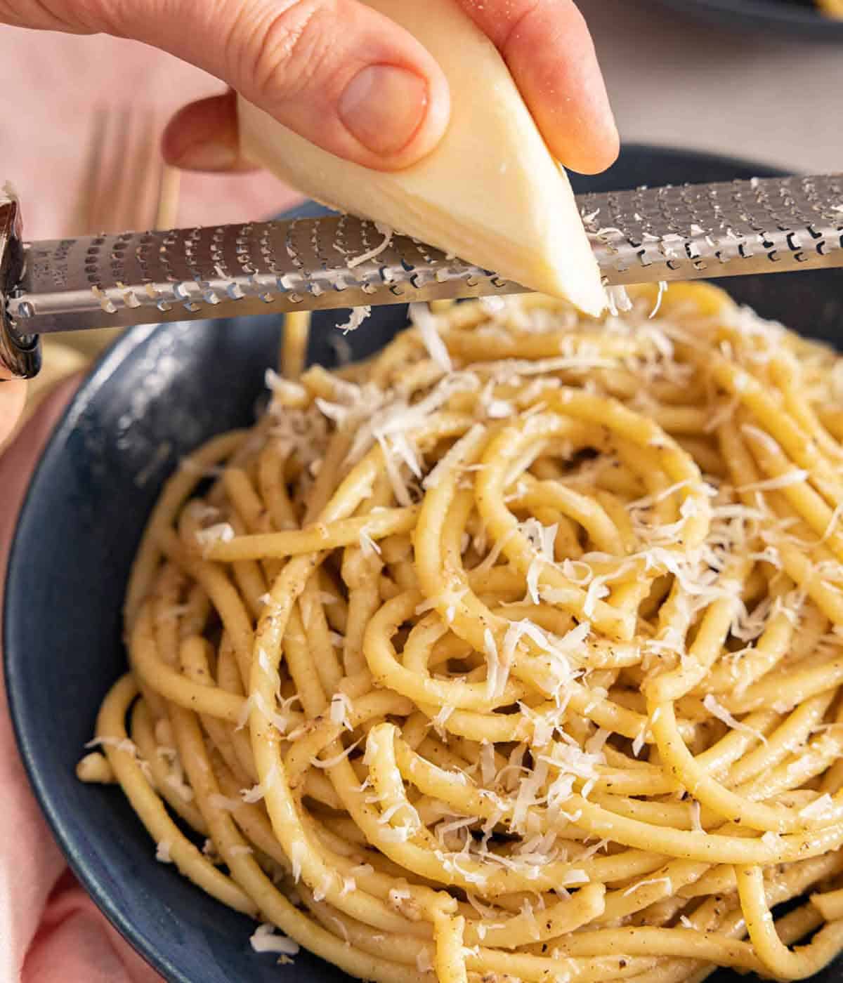 A bowl of cacio e pepe with cheese grated on top with a microplane.