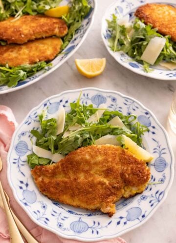A plate with chicken Milanese alongside an arugula salad.