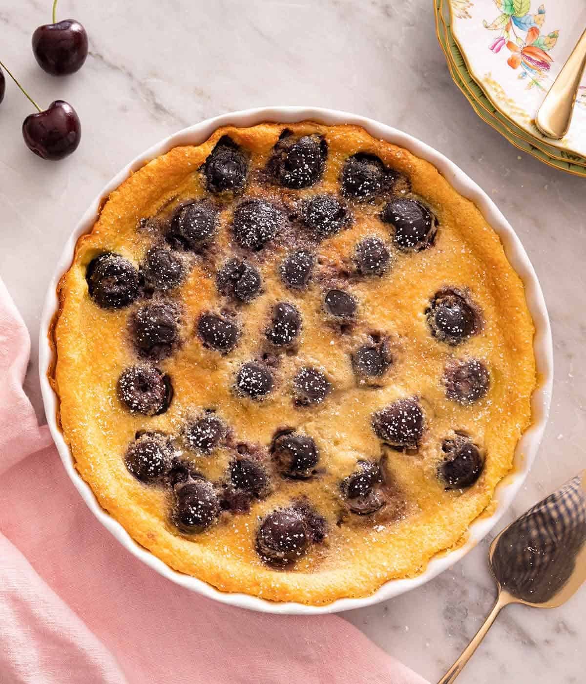 Overhead view of a baking dish with clafoutis and powdered sugar dusted on top.