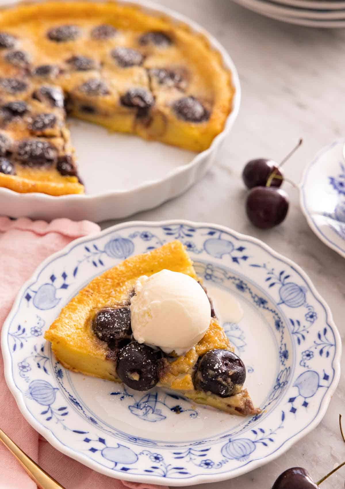 A slice of clafoutis on a plate with a scoop of ice cream on top.