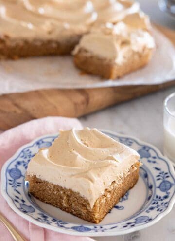 A square slice of peanut butter cake on a plate with the rest in the background.