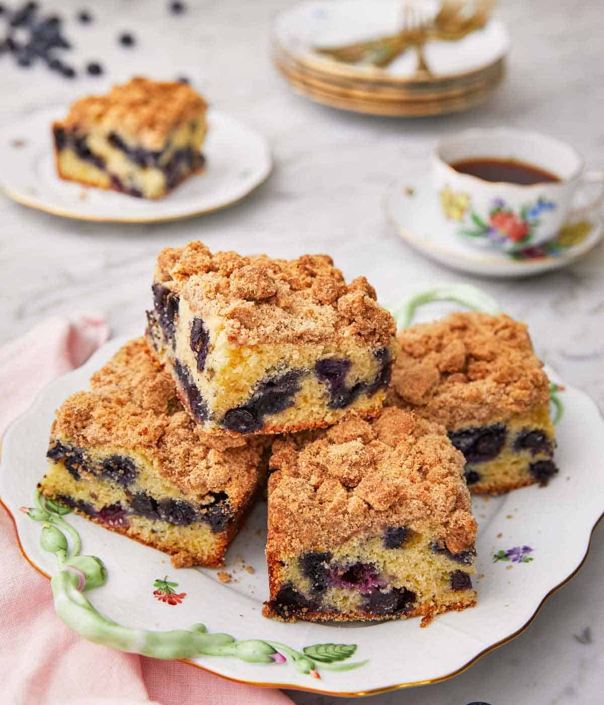 A plate with multiple servings of blueberry coffee cake stacked.