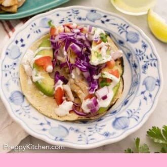 Pinterest graphic of an assembled fish tacos on a plate by a drink.